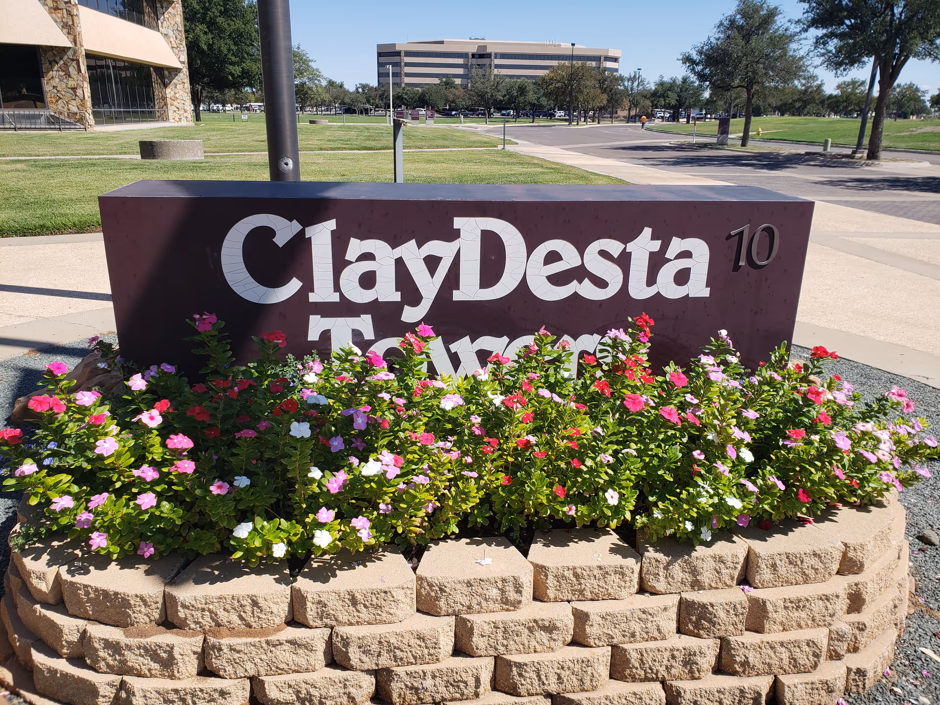 Outdoor sign with colorful flowers in front of a modern building.