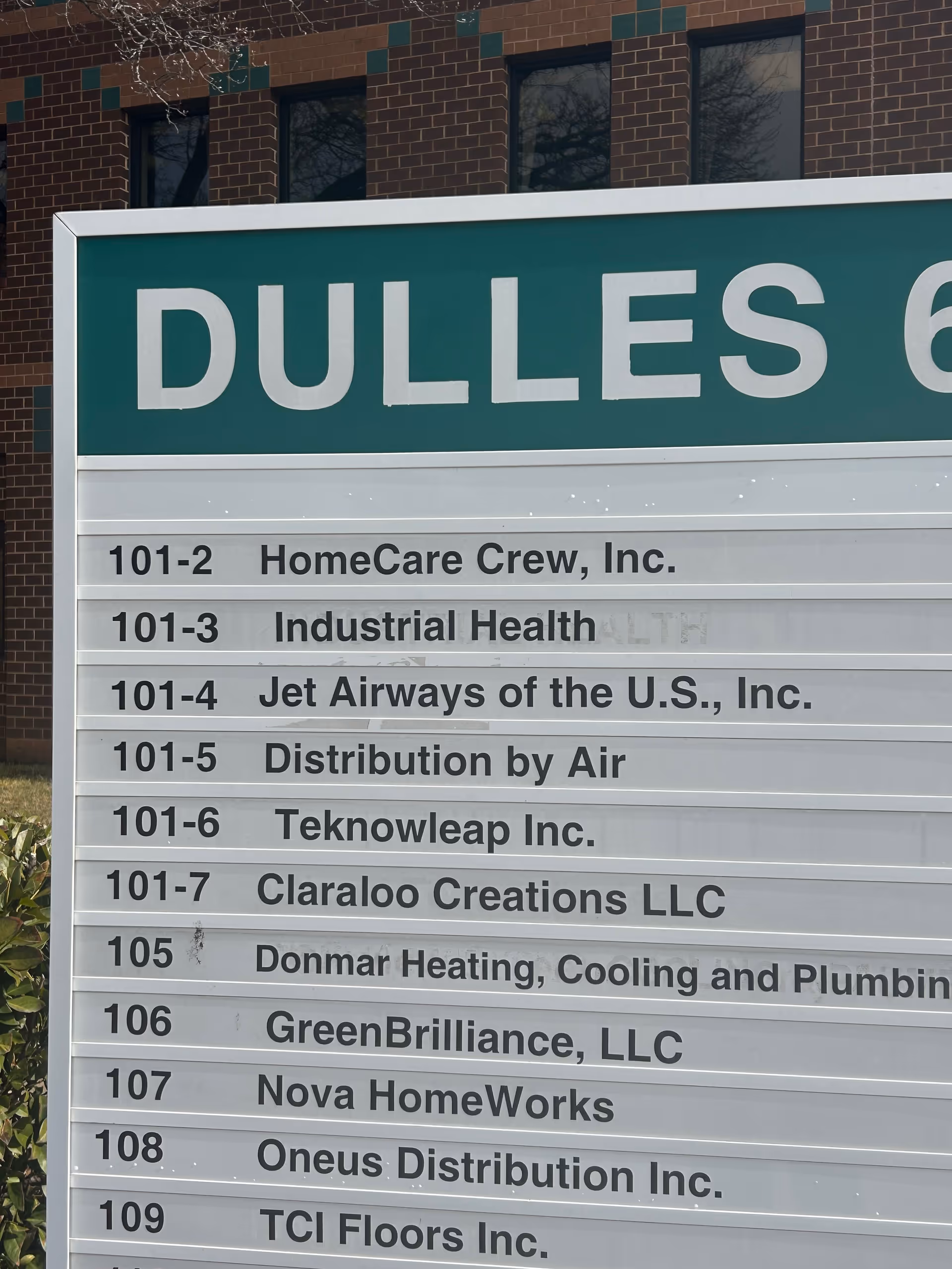 Large exterior signboard with tenant names on a brick building, including HomeCare Crew, Inc.