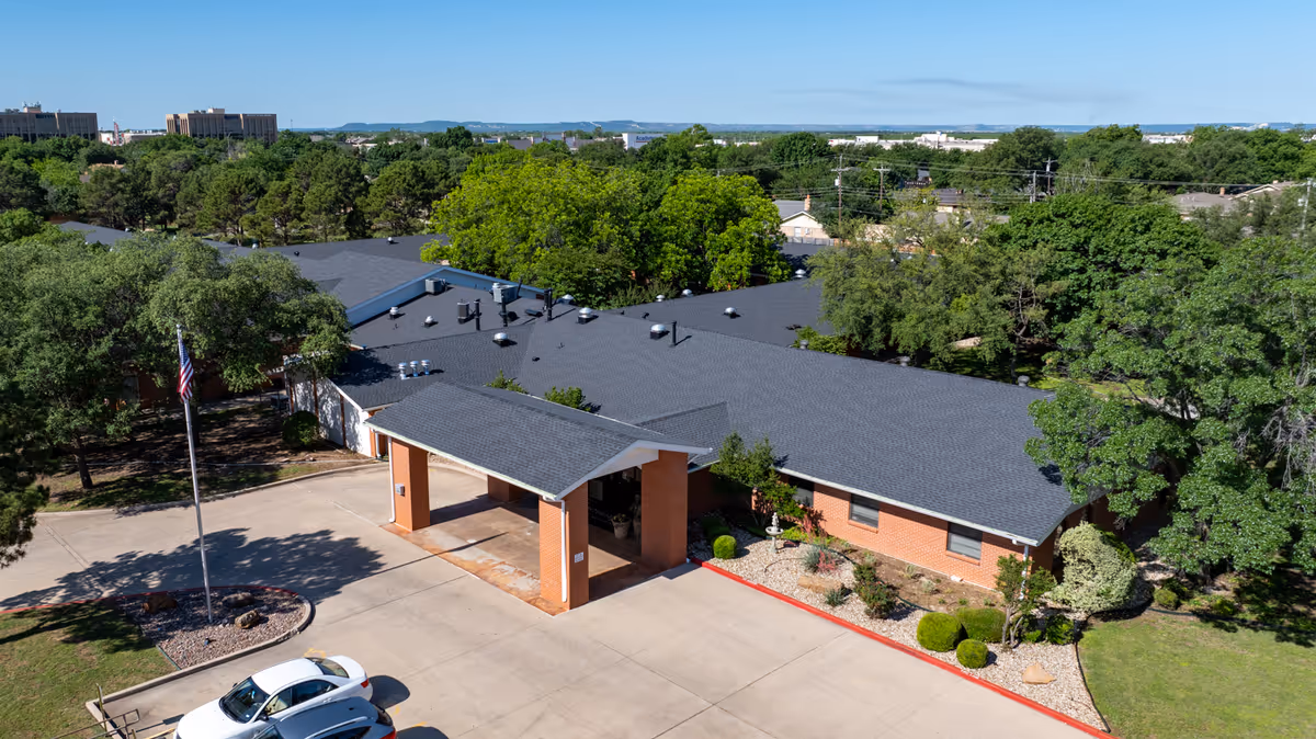 Wisteria Place Nursing and Rehabilitation exterior with a covered entrance, parking, and trees.