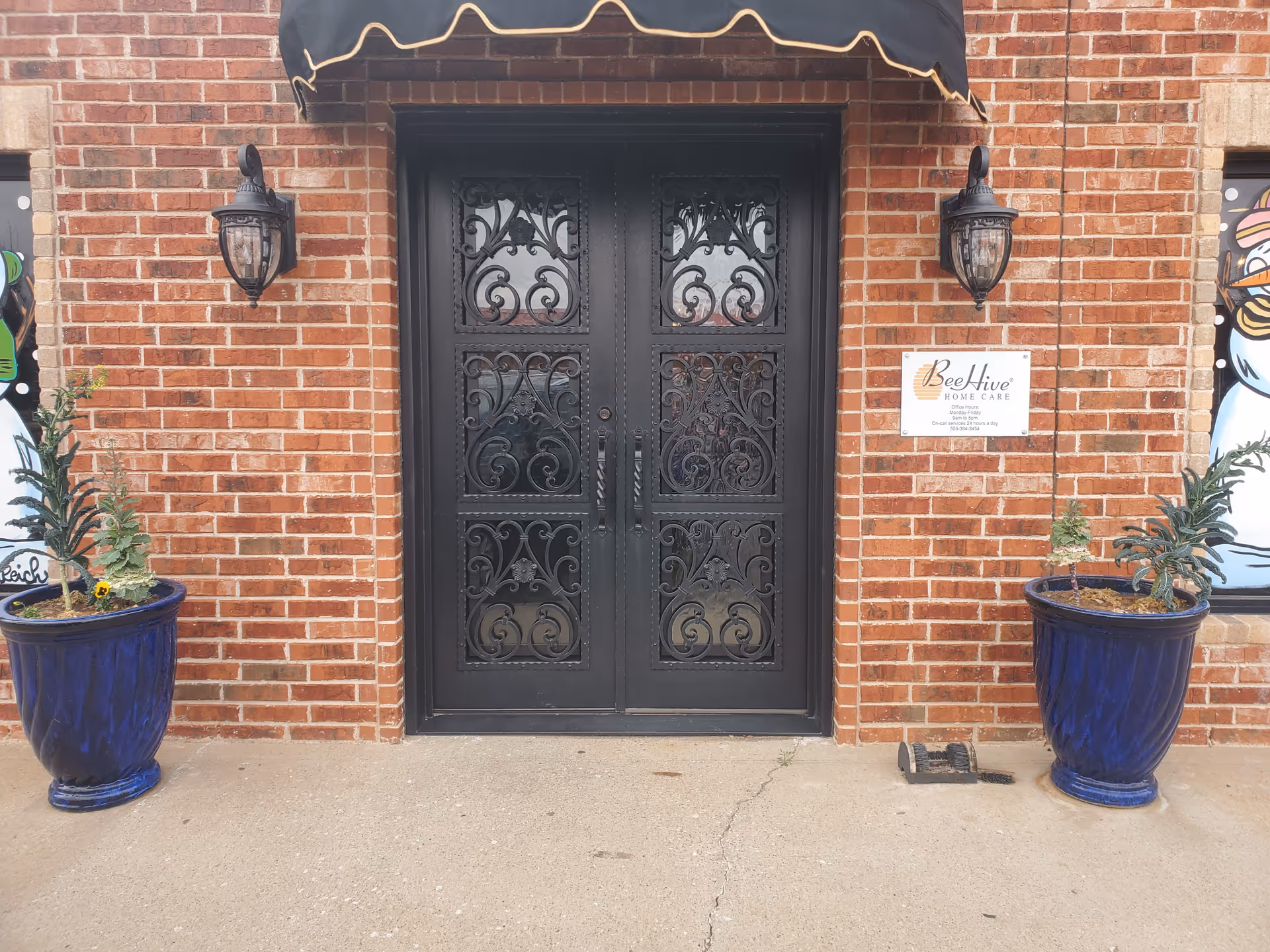 Beehive Home Care of Texas entrance with ornate black double doors and blue planters.