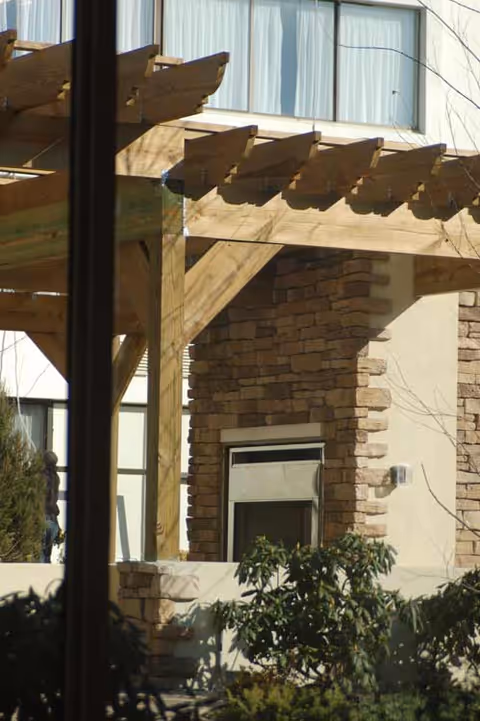 Exterior view of Bedrock at Home facility with stone wall and wooden pergola.