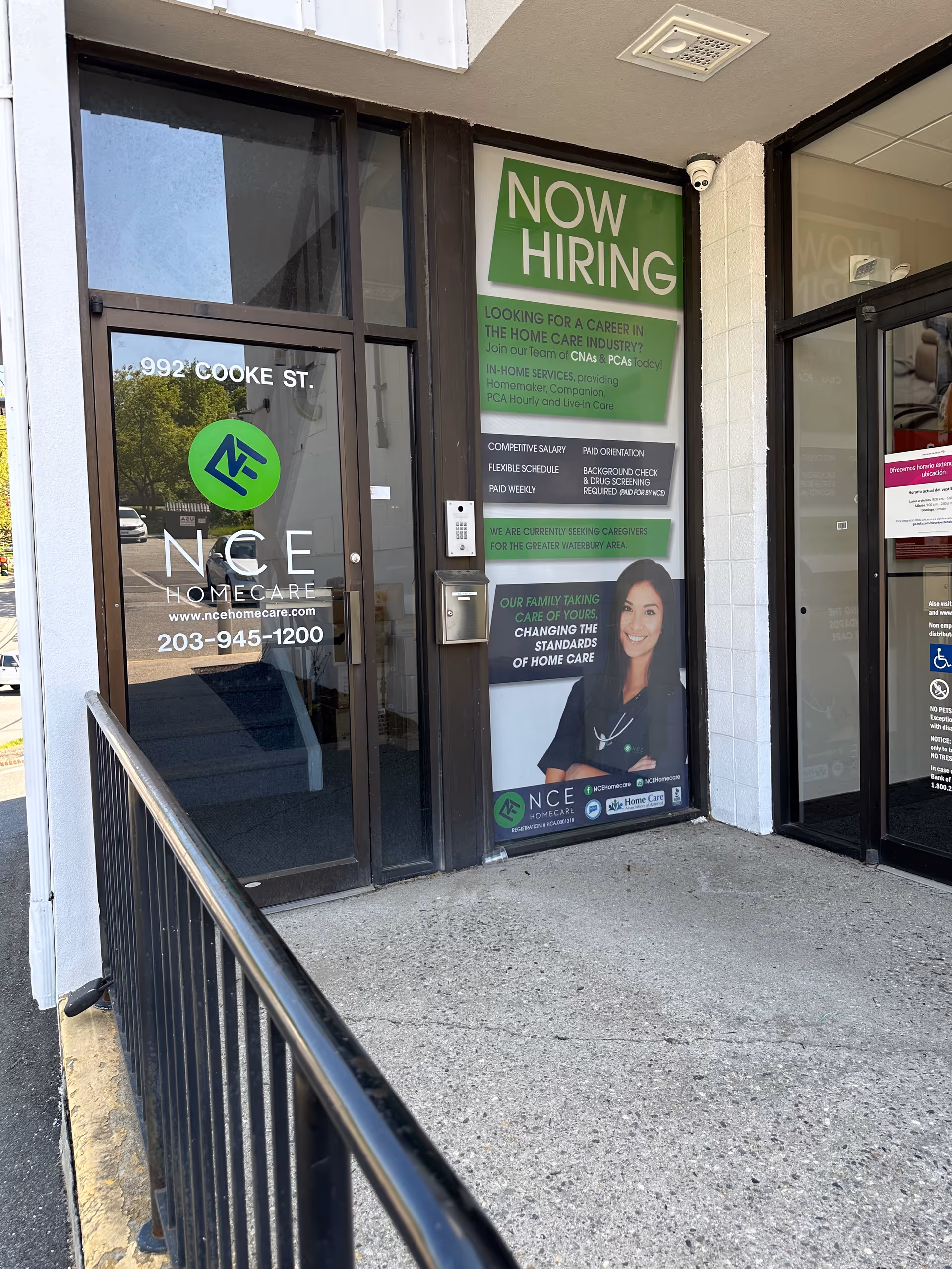 Exterior view of NCE Homecare entrance with Now Hiring sign and glass doors.