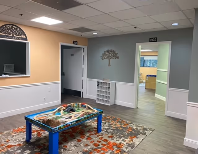 Play table on a colorful rug in a pastel interior hallway of a senior living facility.