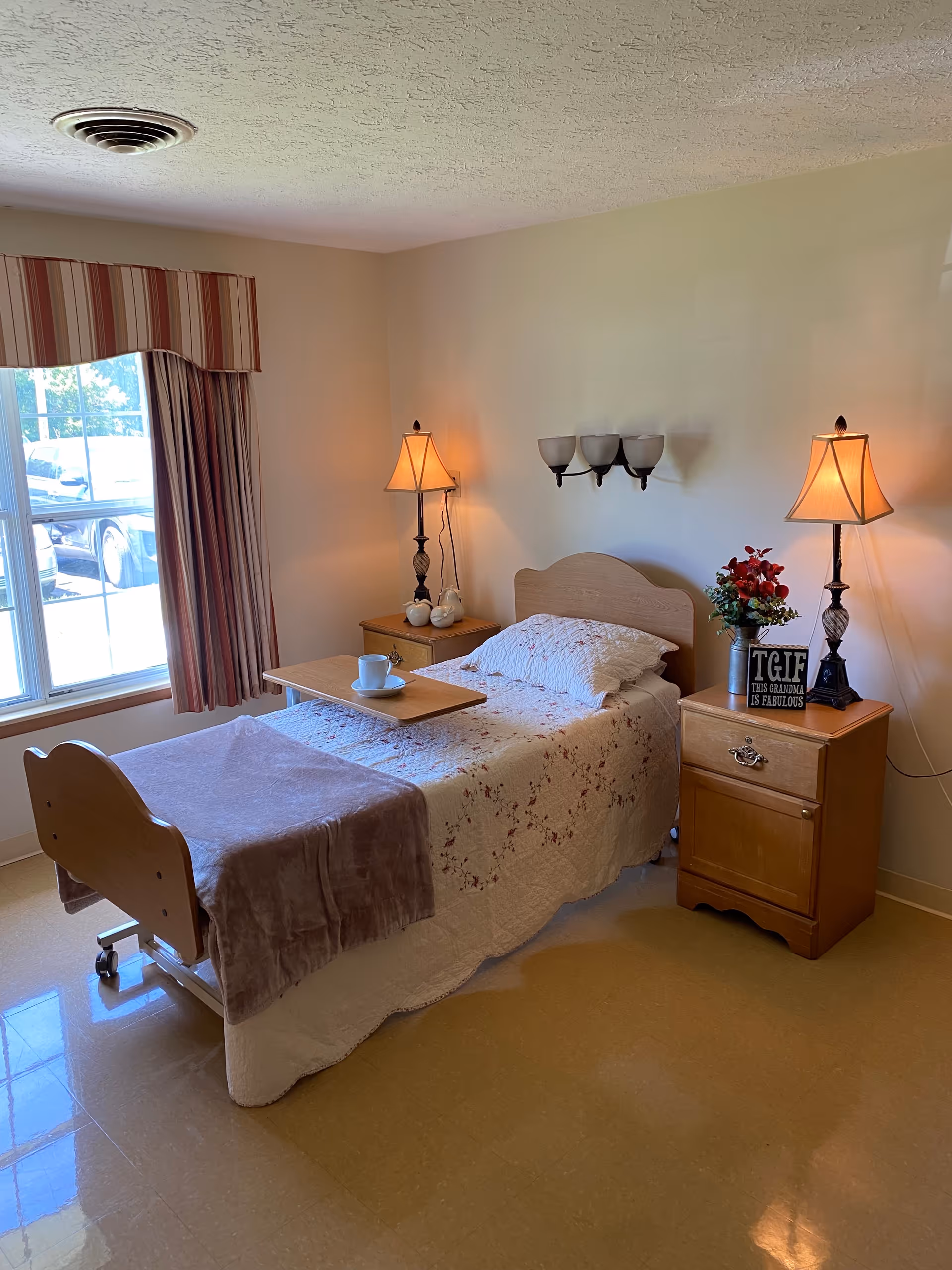Sunlit bedroom with a single bed, dual nightstands, lamps, and a breakfast tray.