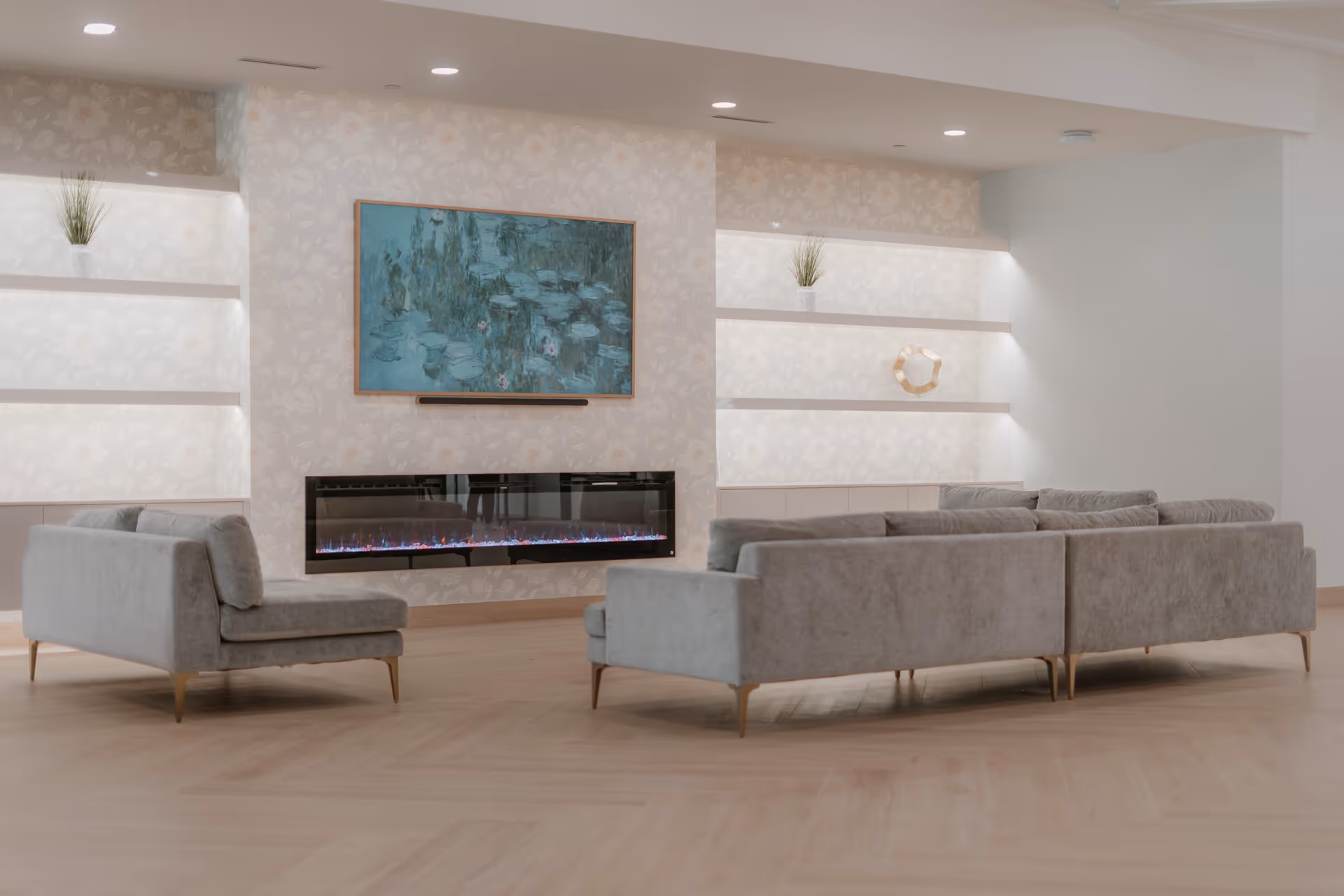 Elegant modern lounge with a wall fireplace, mounted TV, and grey sectional seating.