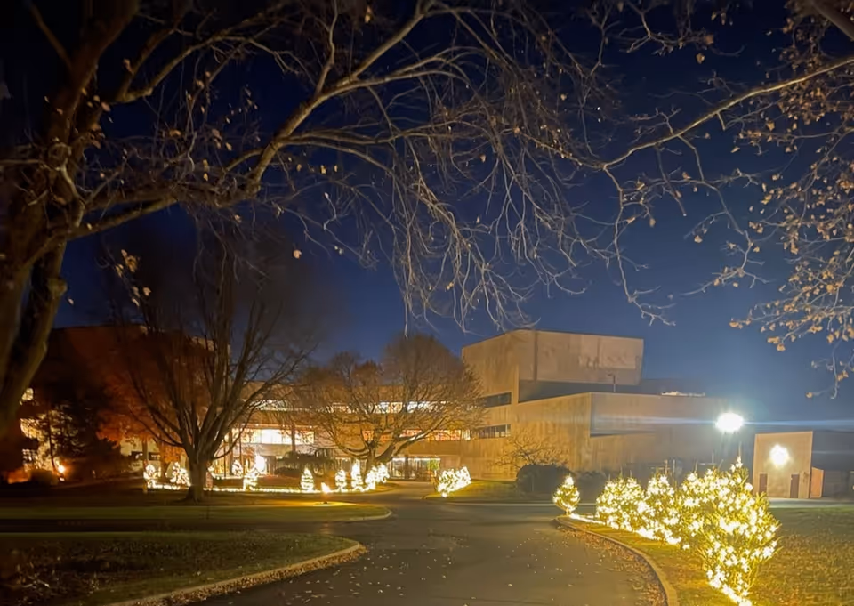Night exterior of Connecticut Hospice with illuminated holiday lights along the curved entrance road.