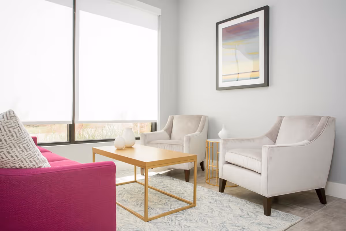 Bright modern living room in a senior facility with pink sofa and beige chairs.