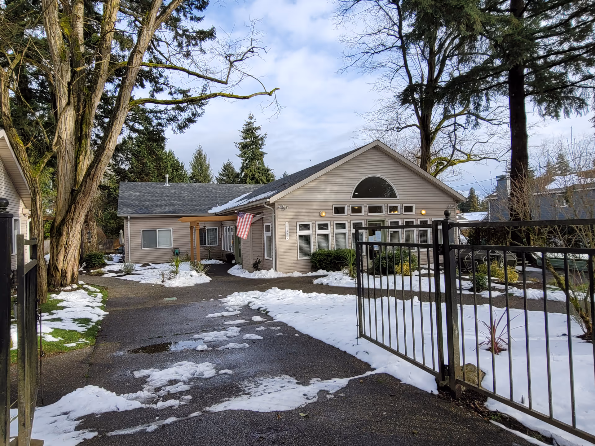 Exterior view of Evergreen Adult Family Homes building with snow and gate.