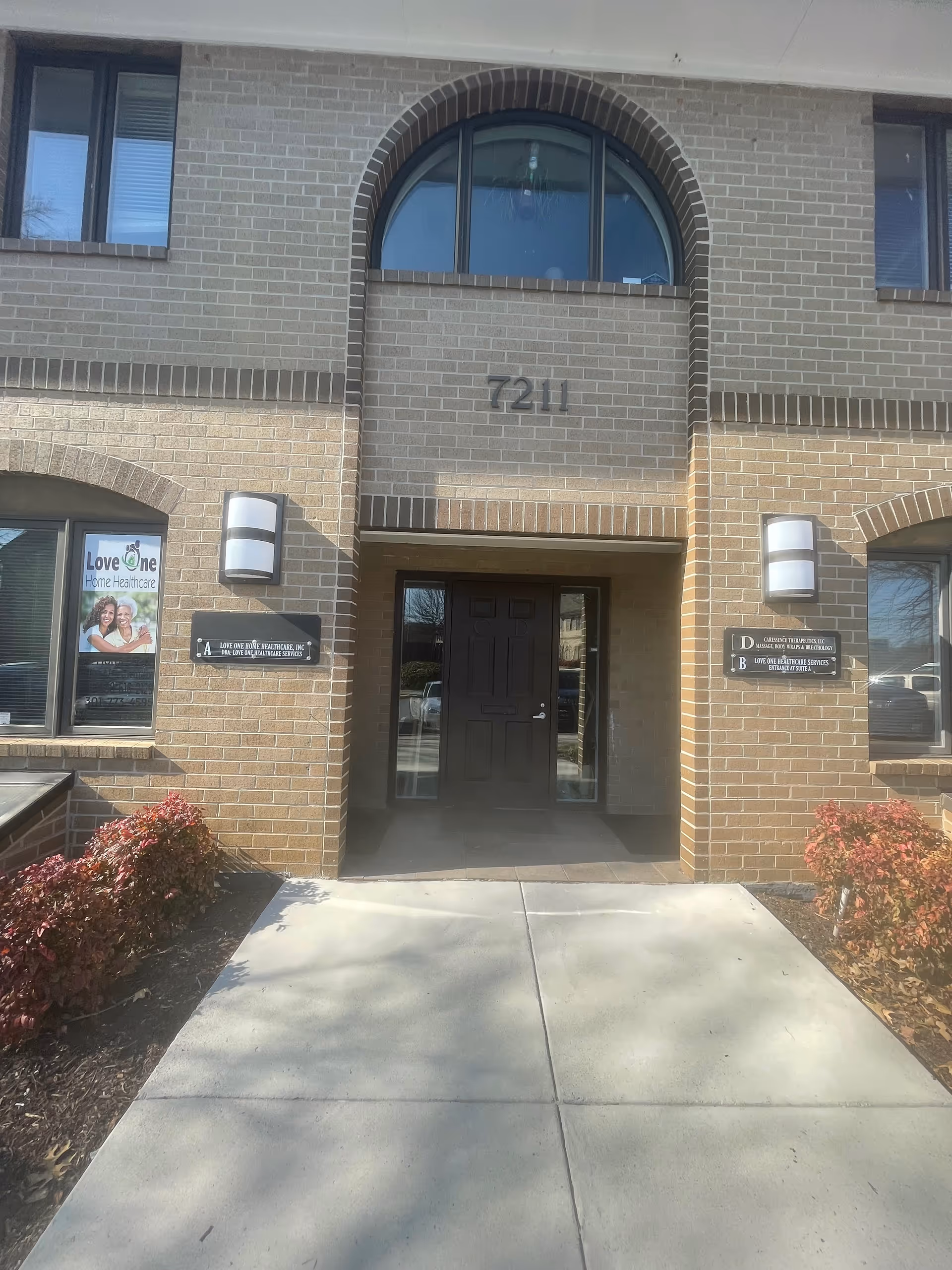 Exterior entrance of Love One Home Healthcare building with brick facade and arched window above