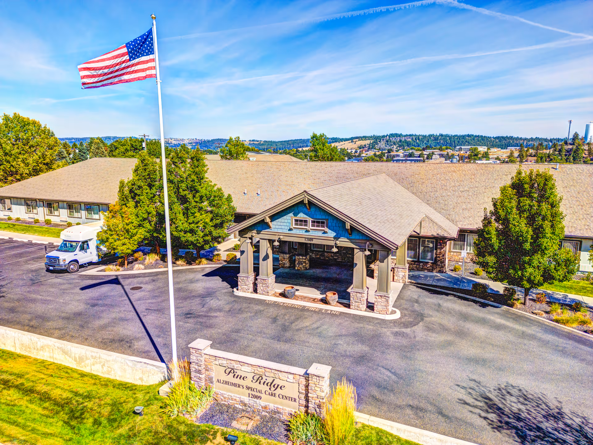 Aerial view of Pine Ridge Alzheimer's Special Care Center entrance with flag and signage.