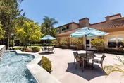 Outdoor patio with pool, umbrellas, and seating near a senior living building.
