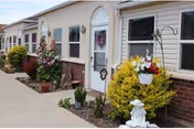 Row of light-colored, single-story retirement units with doors, windows, and landscaped planters.