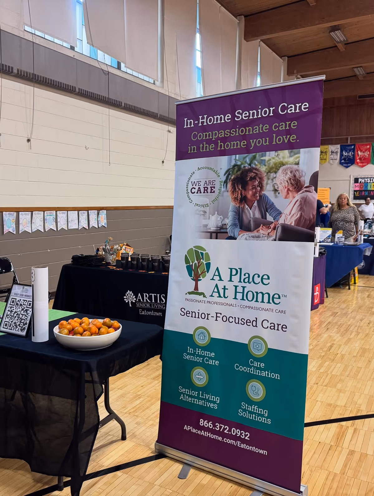 A Place At Home Eatontown banner stands beside vendor tables at an indoor event.