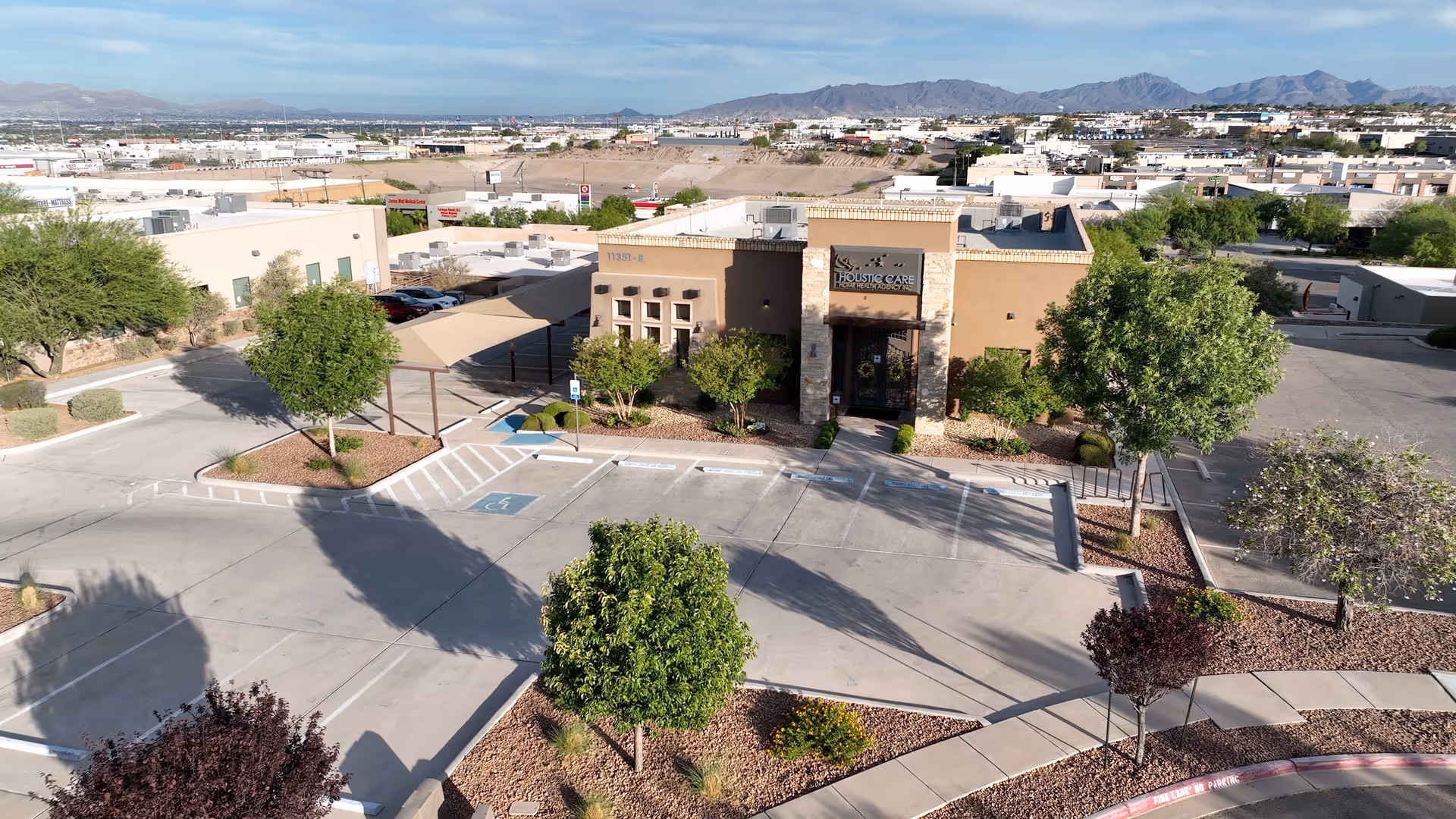 Aerial view of Holistic Care Home Health Agency building with parking and desert landscaping.