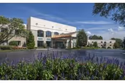 Front exterior of Delmar Gardens of Meramec Valley with purple flowers.