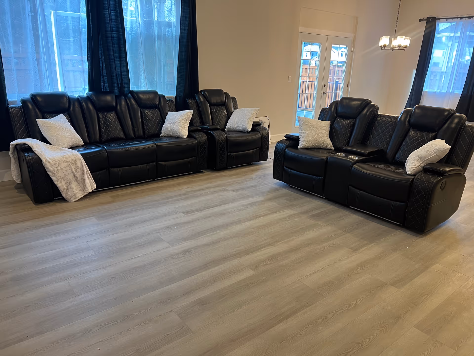 Spacious living room with black leather sofas and white pillows.