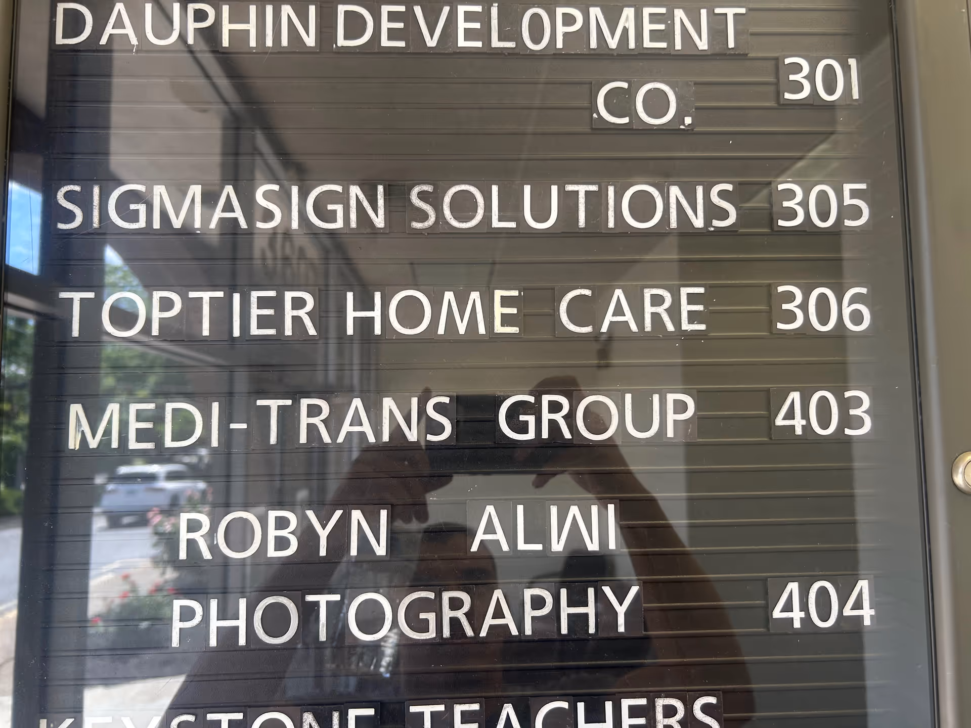 Reflective glass directory board listing tenants with suite numbers, including TopTier Home Care 306.