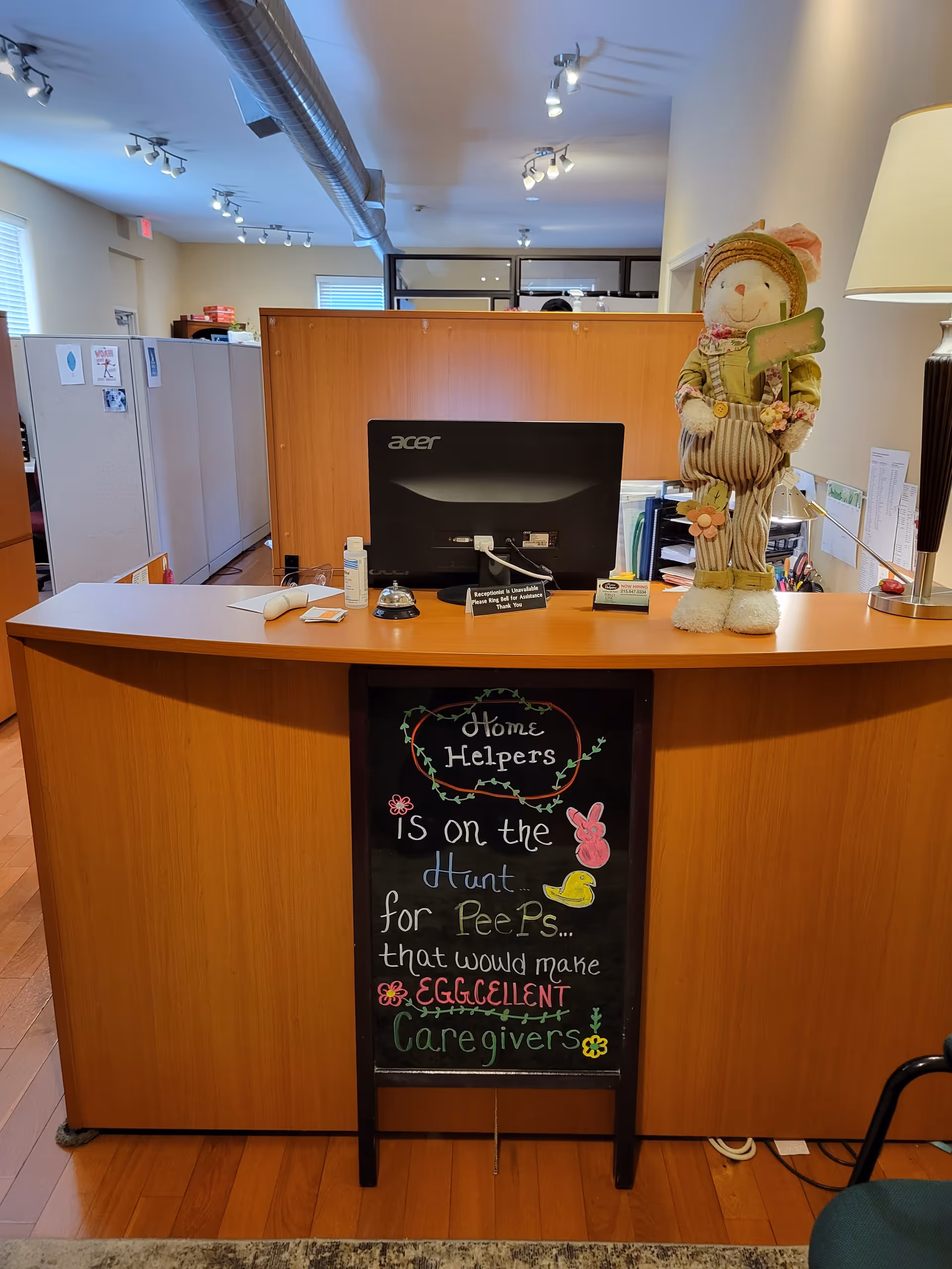 Reception desk with computer, holiday snowman, and chalkboard sign promoting caregivers