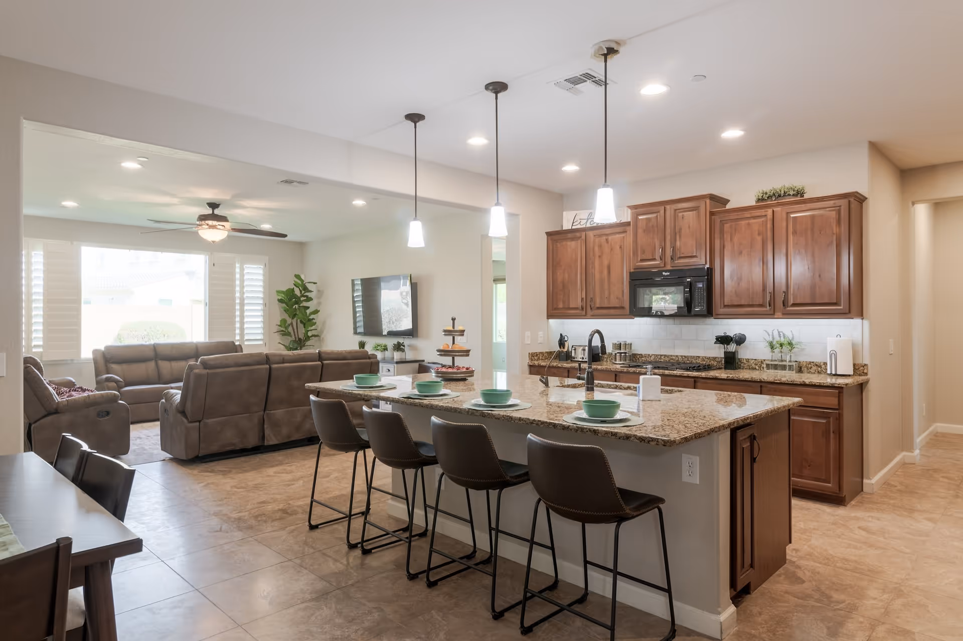 Open-concept living area with kitchen island, bar stools, and neutral decor.