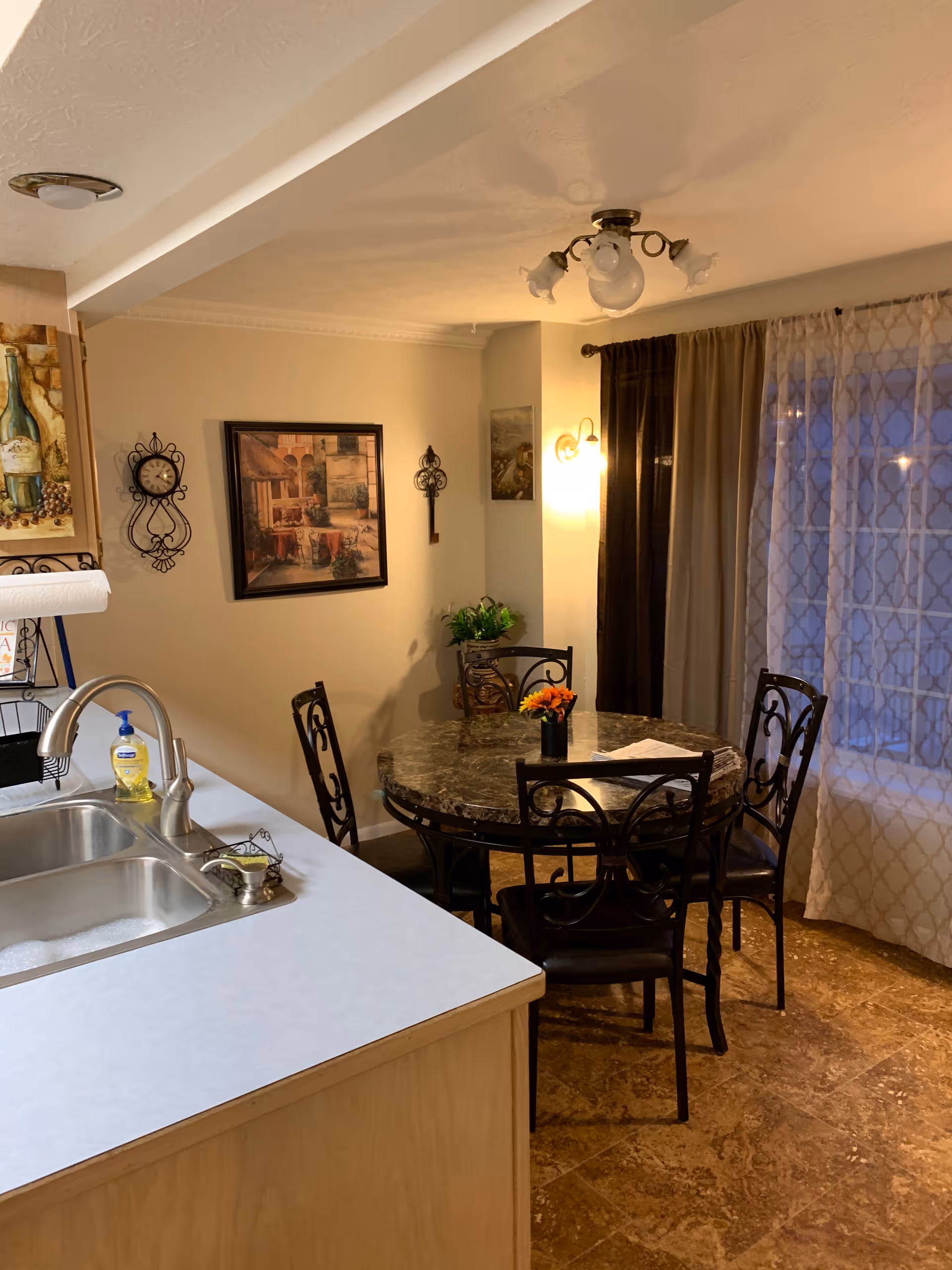 A small dining area with a round marble table and metal chairs beside a kitchen counter.