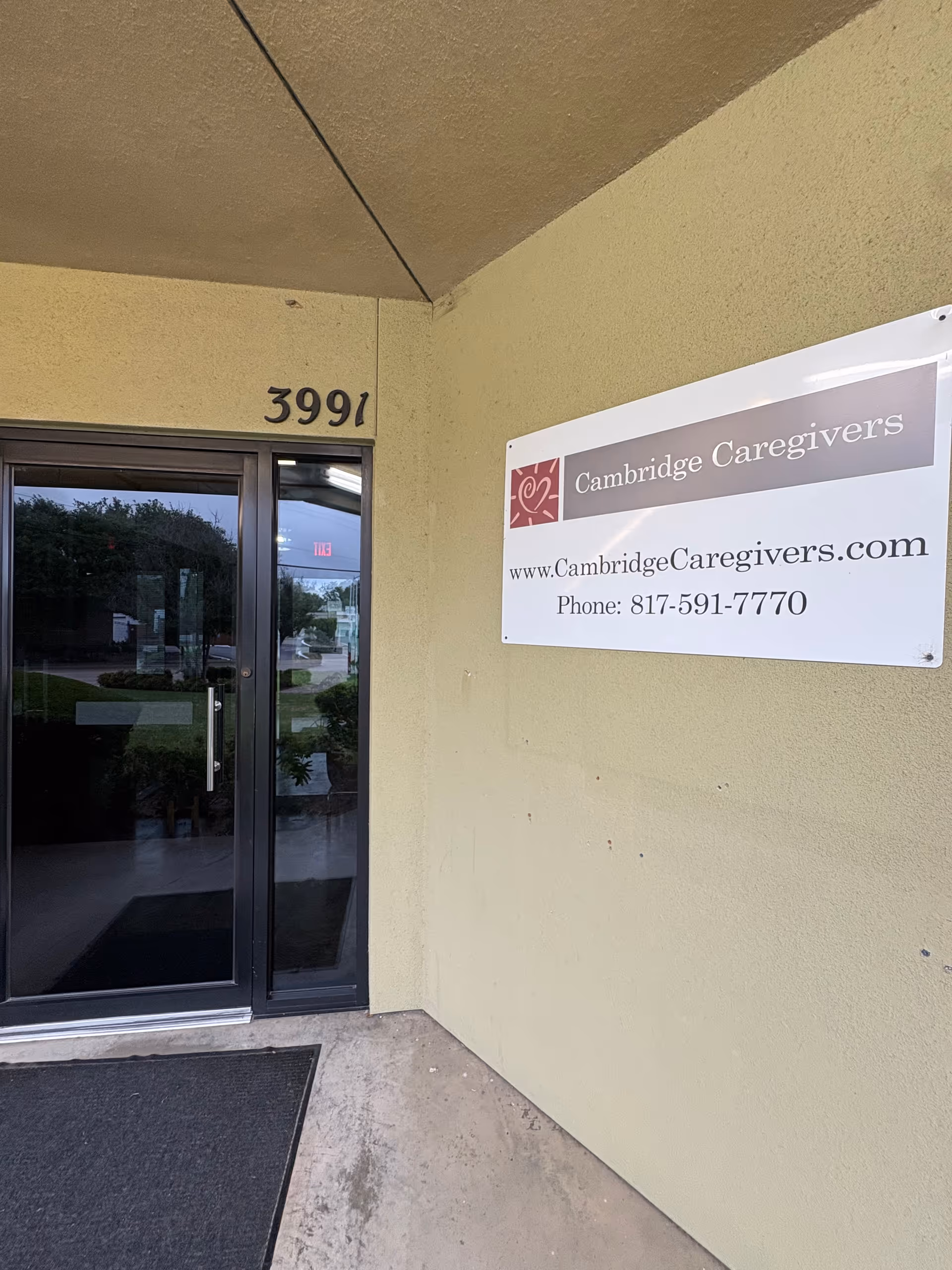 Front entrance of Cambridge Caregivers building with glass door and sign.