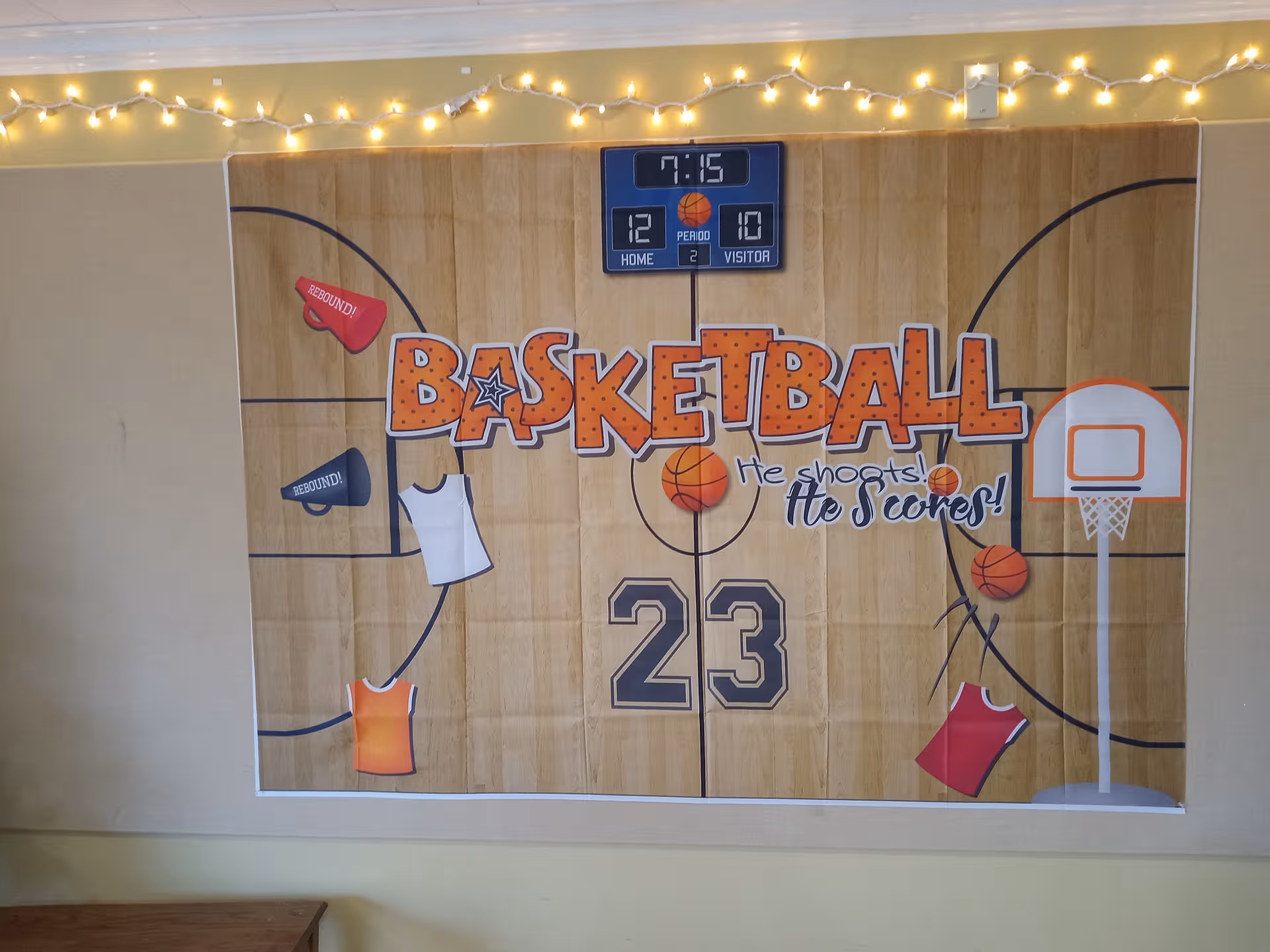 Indoor mural depicts a basketball court with a scoreboard and string lights along the wall.