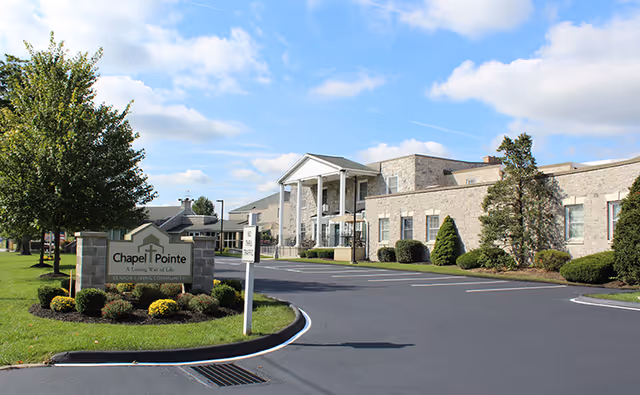 Exterior view of Chapel Pointe at Carlisle with entrance, sign, and curved driveway.