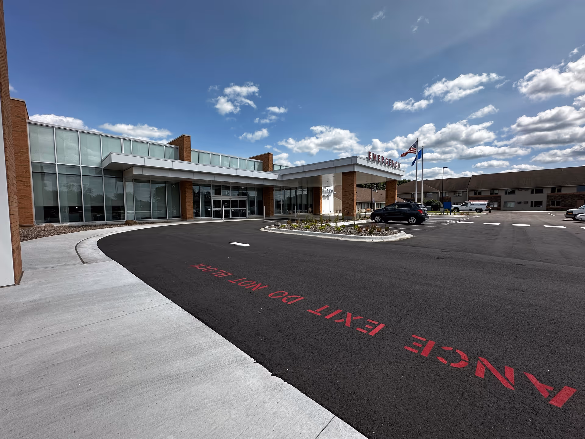 Exterior view of Paynesville Health Care Center front entrance with glass walls and emergency sign.