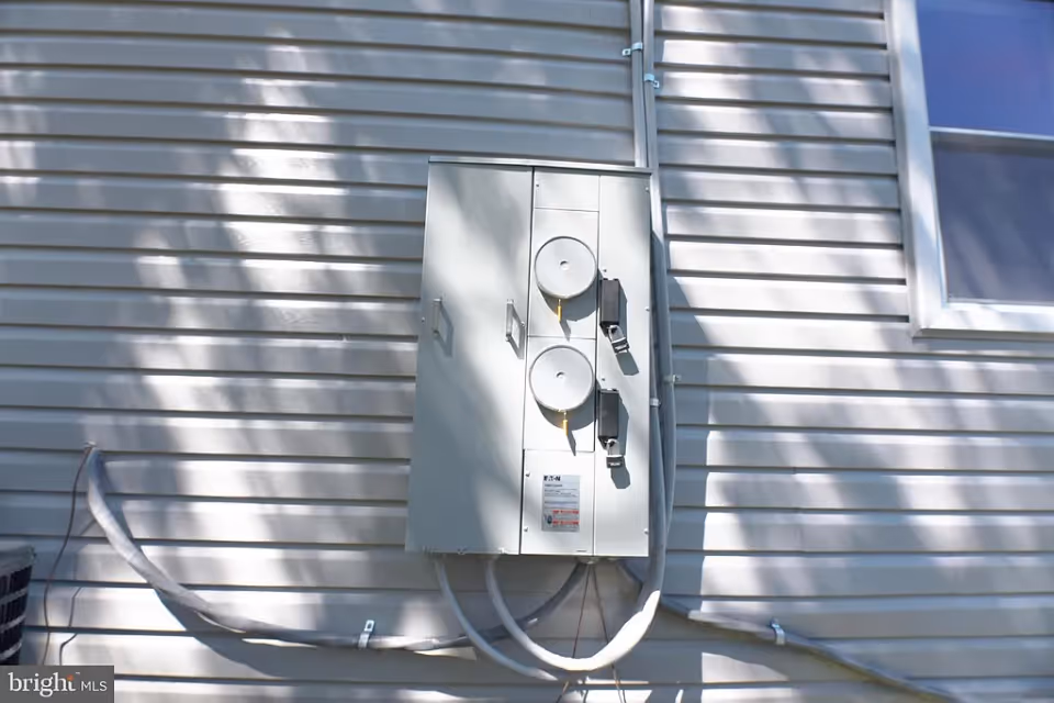 Electric service panel mounted on the exterior wall of a building.