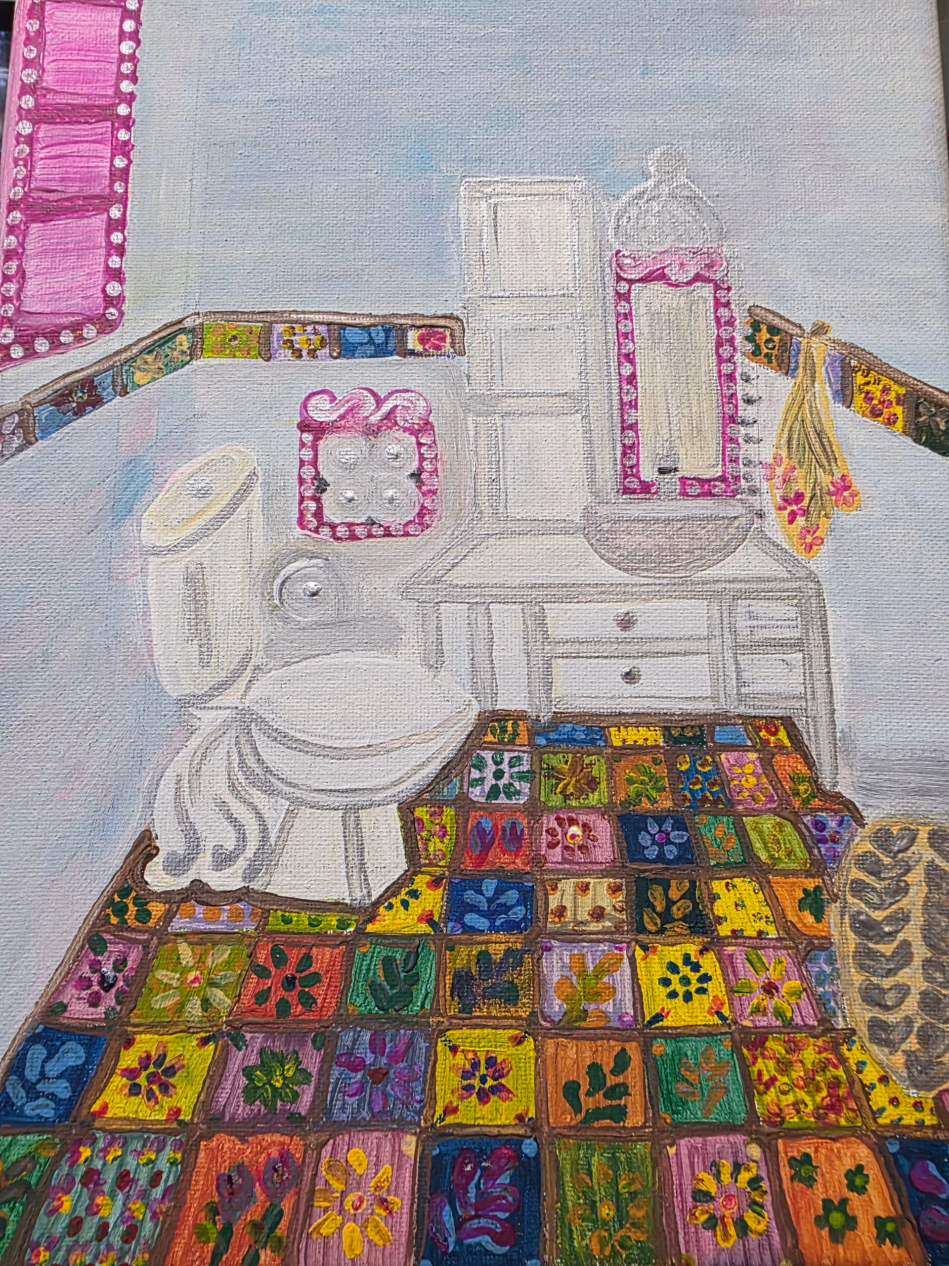 Bathroom scene featuring a sink, toilet, dresser, pink-framed mirror, and colorful patchwork rug.