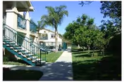 Exterior view of Abbey Road Villa showing walkway, stairs, lawn, and palm trees.