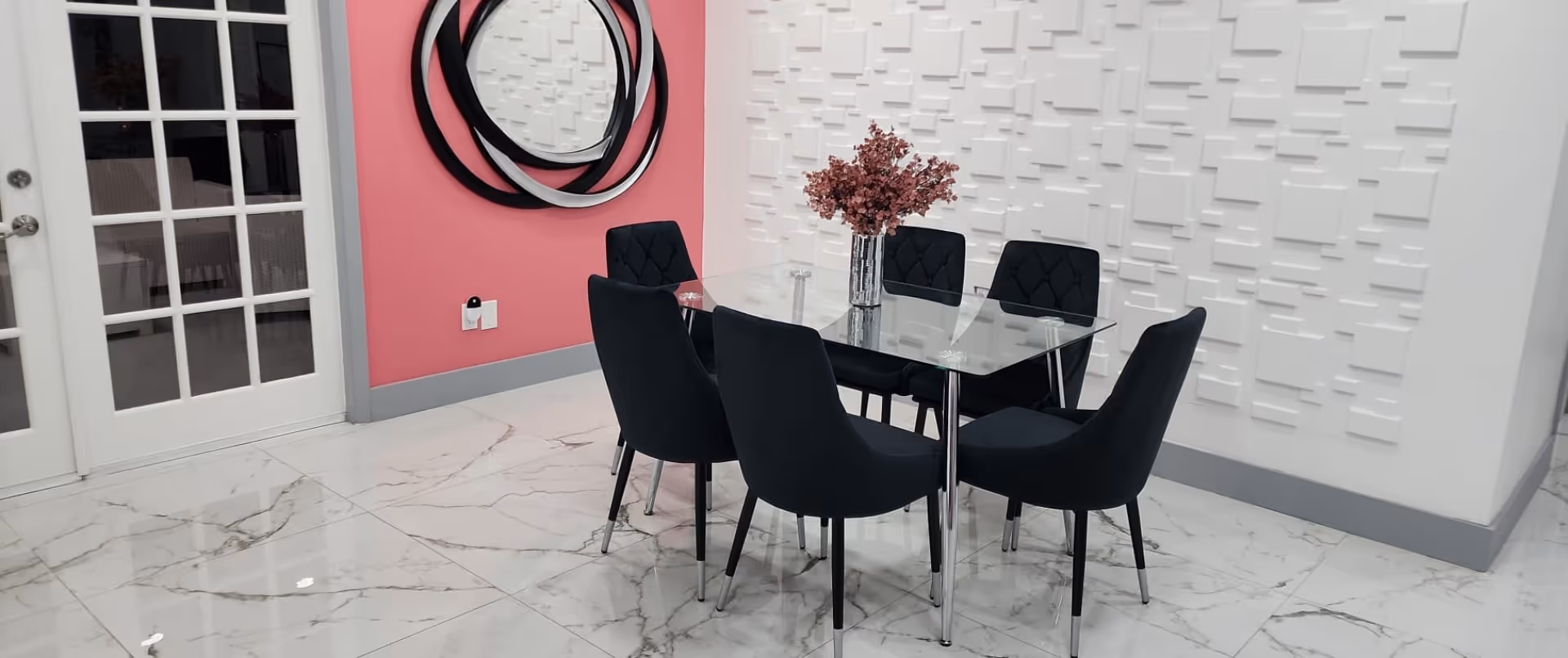 A modern dining area featuring a glass table and six black chairs with a decorative pink wall.