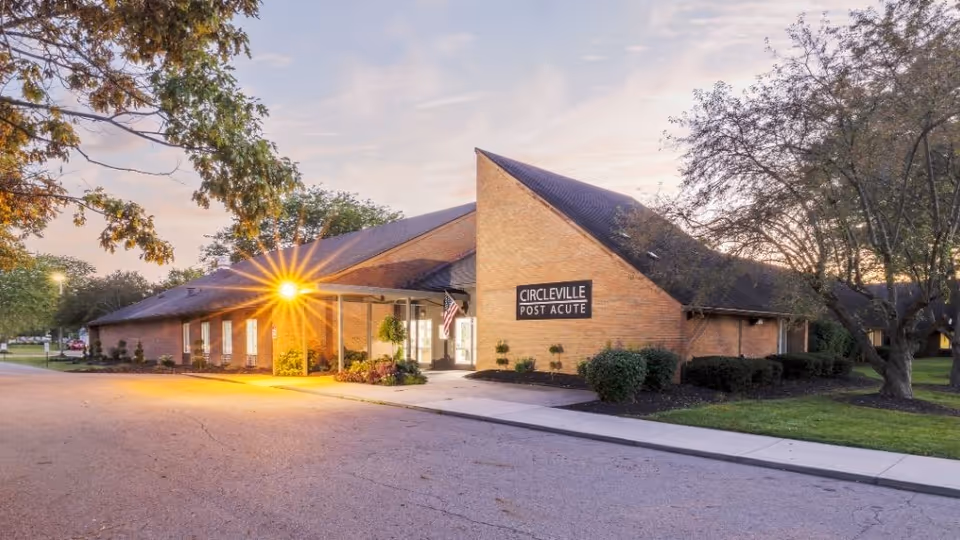 Brick senior care facility exterior at dusk, lit entrance, and Circleville Post Acute sign.
