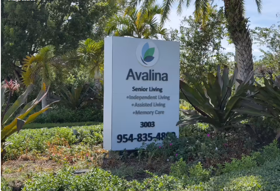 Outdoor sign for Avalina Senior Living amid tropical landscaping.