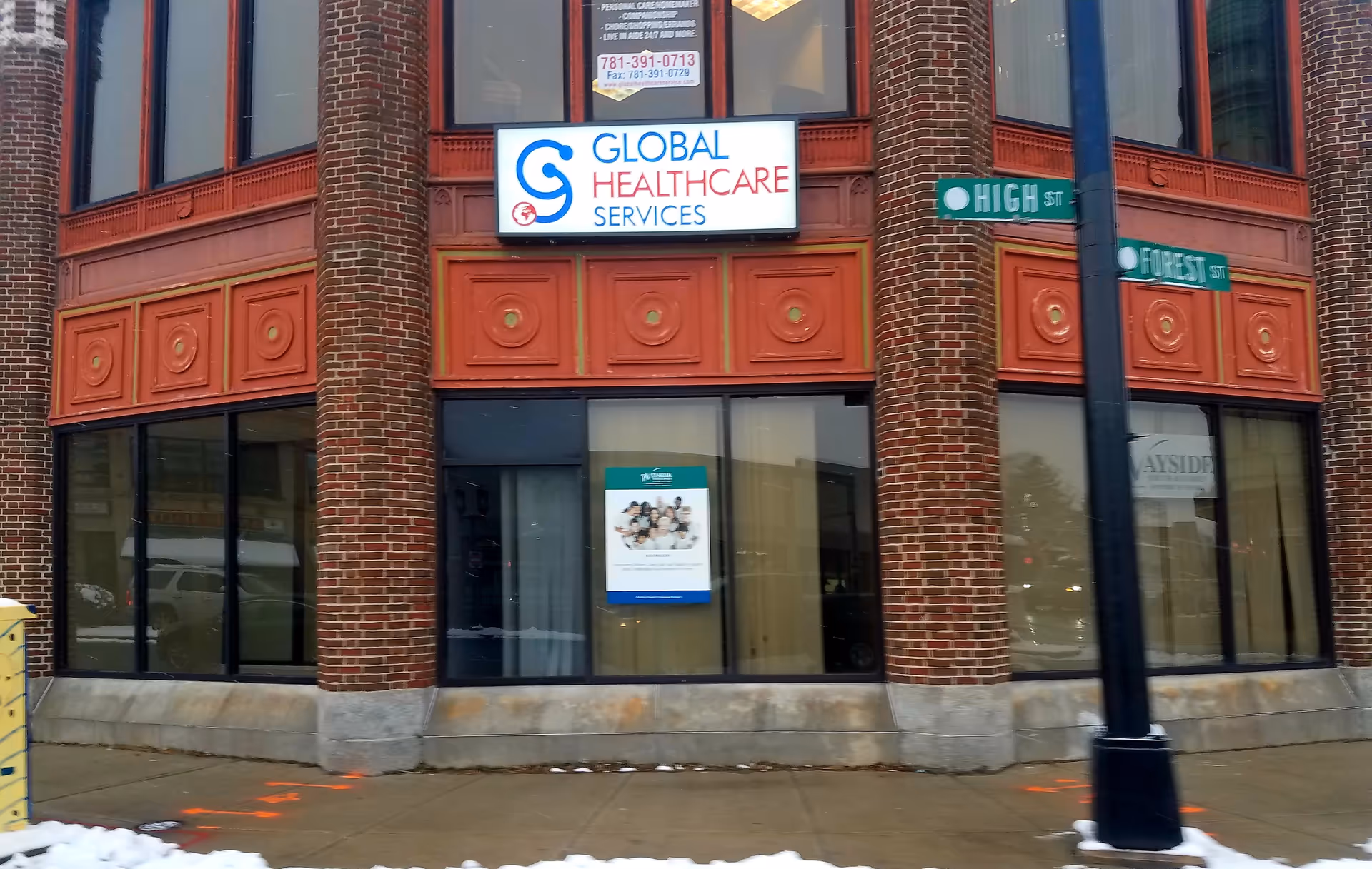 Brick building corner with a Global Healthcare Services sign and High Street street signs.