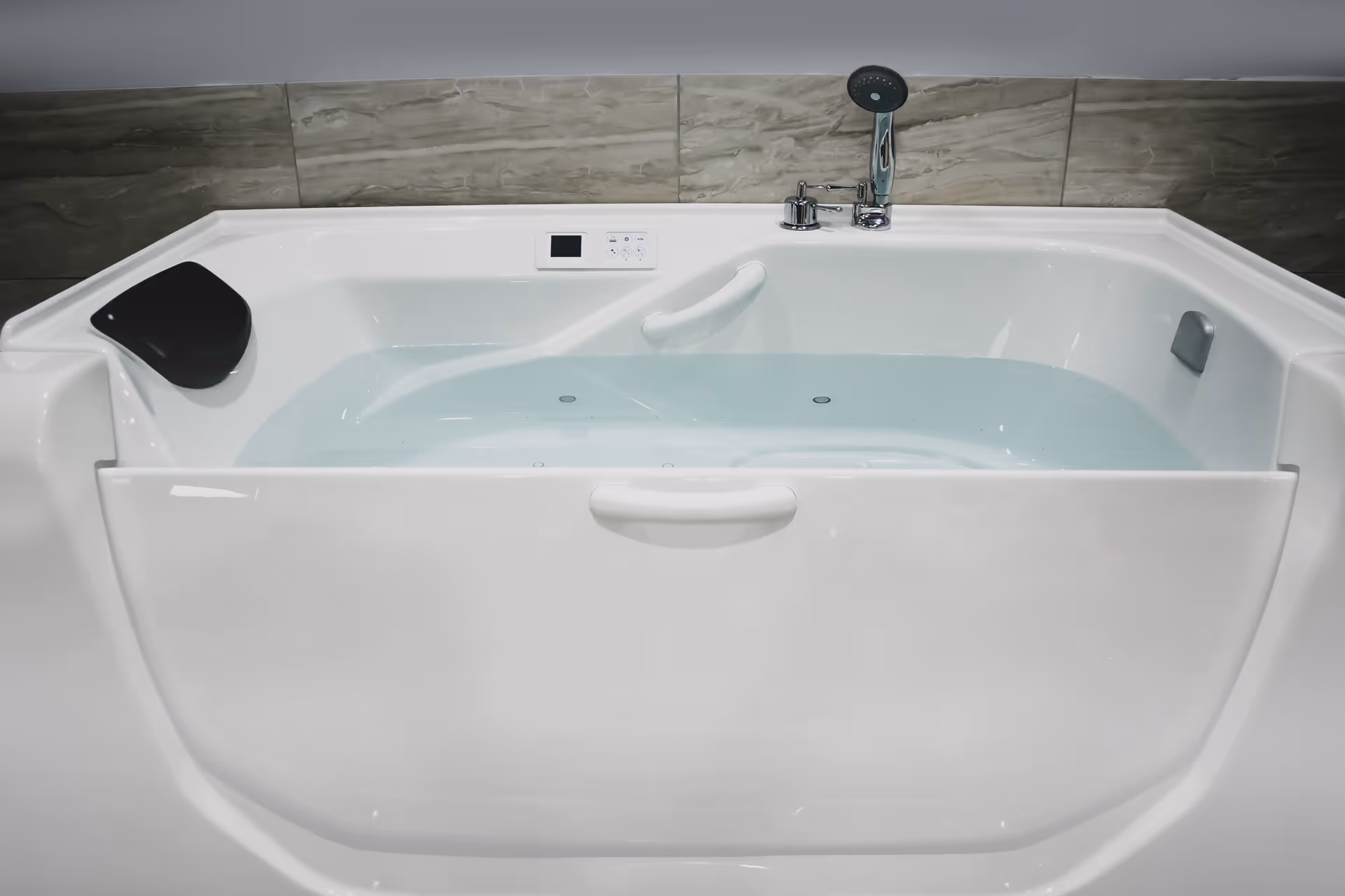 Large white spa bathtub with water and wall tile backdrop