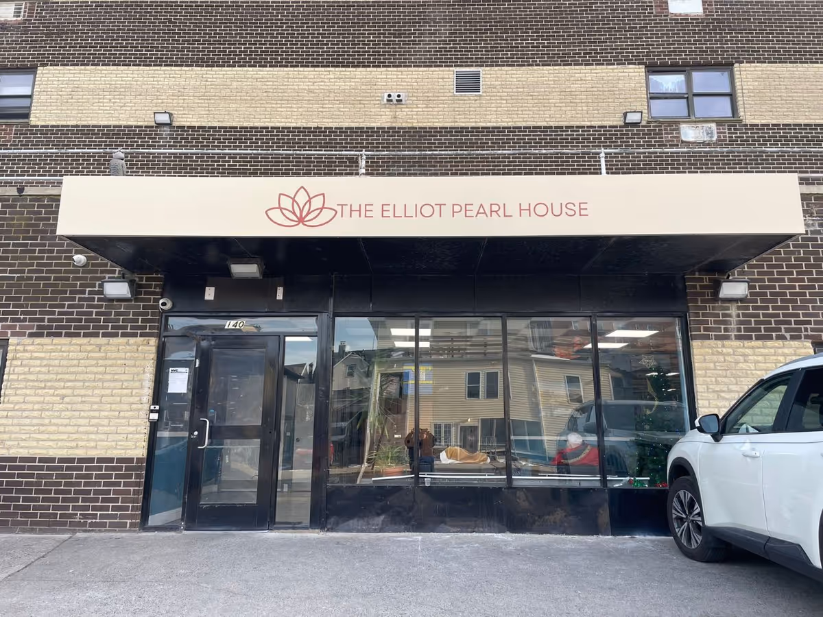 Brick exterior of a facility with glass doors and a sign reading The Elliot Pearl House.