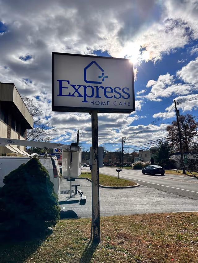 A tall Express Home Care sign stands by the road under a blue sky.