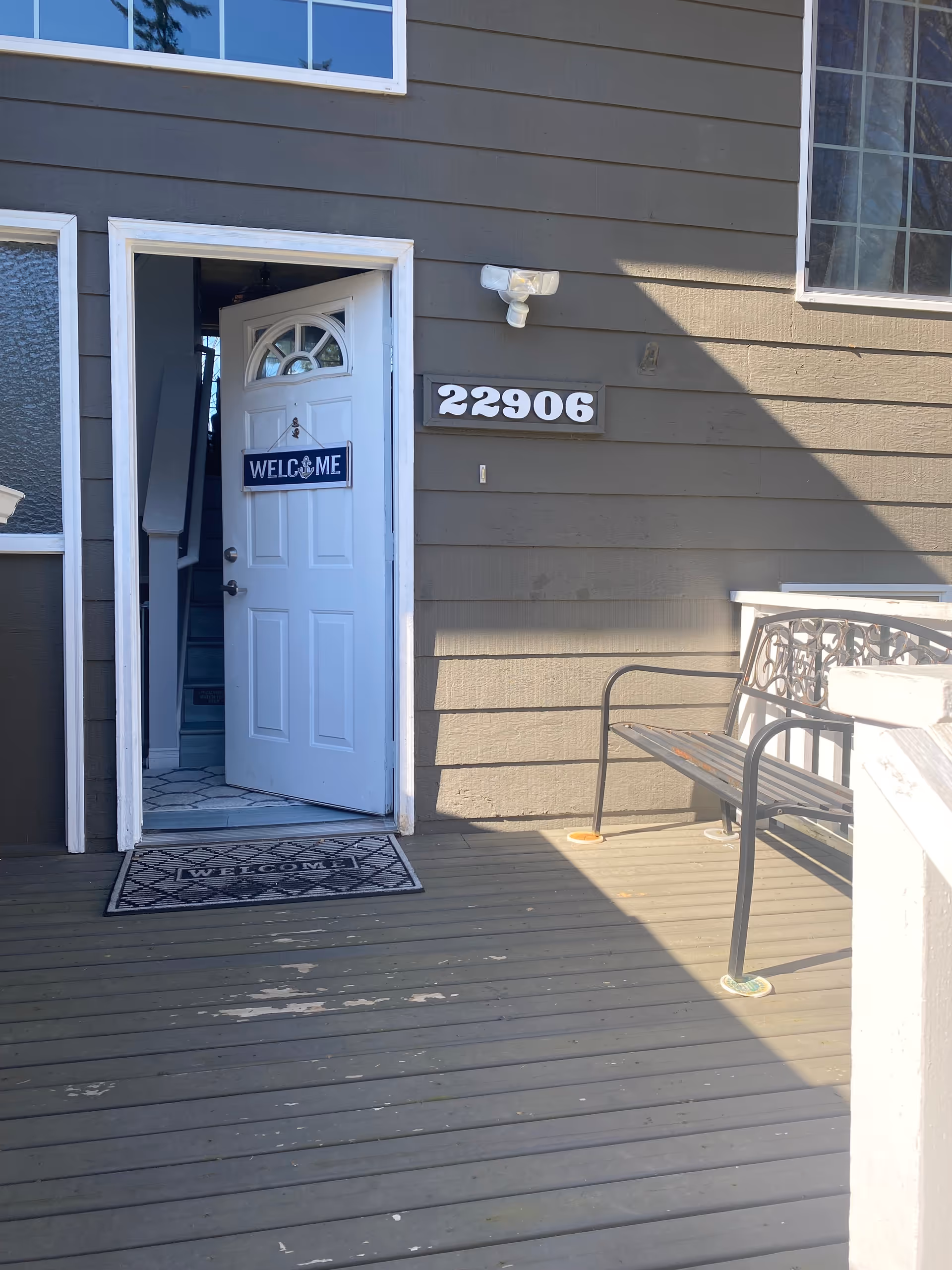 Exterior view of a senior living home entrance with a welcome mat, bench, and address 22906.
