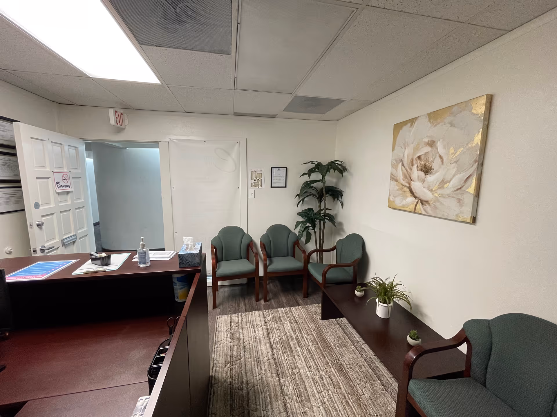 Interior lobby of Compassionate Care LLC with desk, chairs, plants, and wall art.