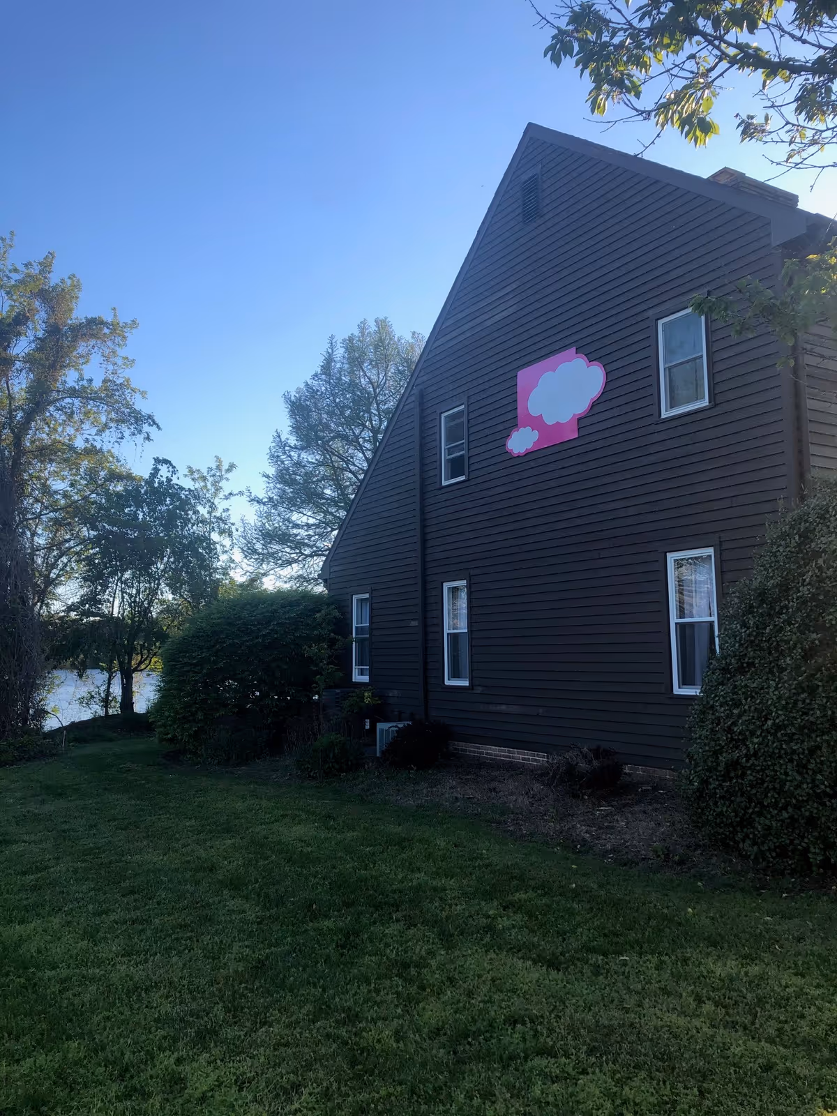 Brown two-story building with pink cloud sign, green lawn, and blue sky.