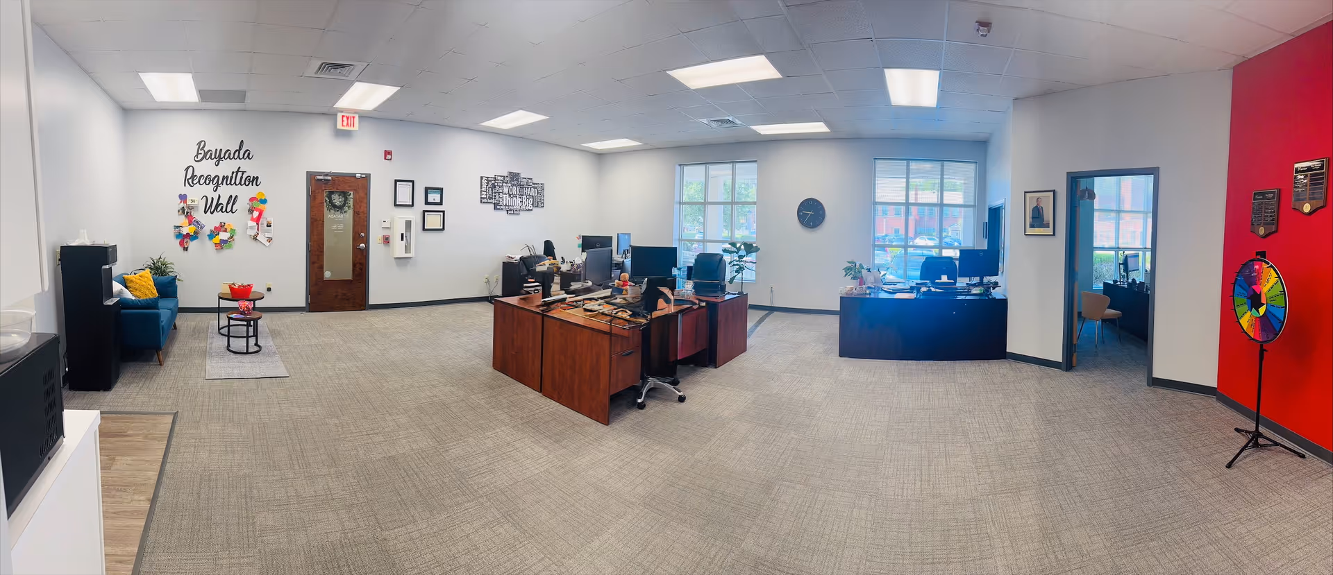 Open indoor reception area with desks, computers, seating, and a Bayada Recognition Wall.