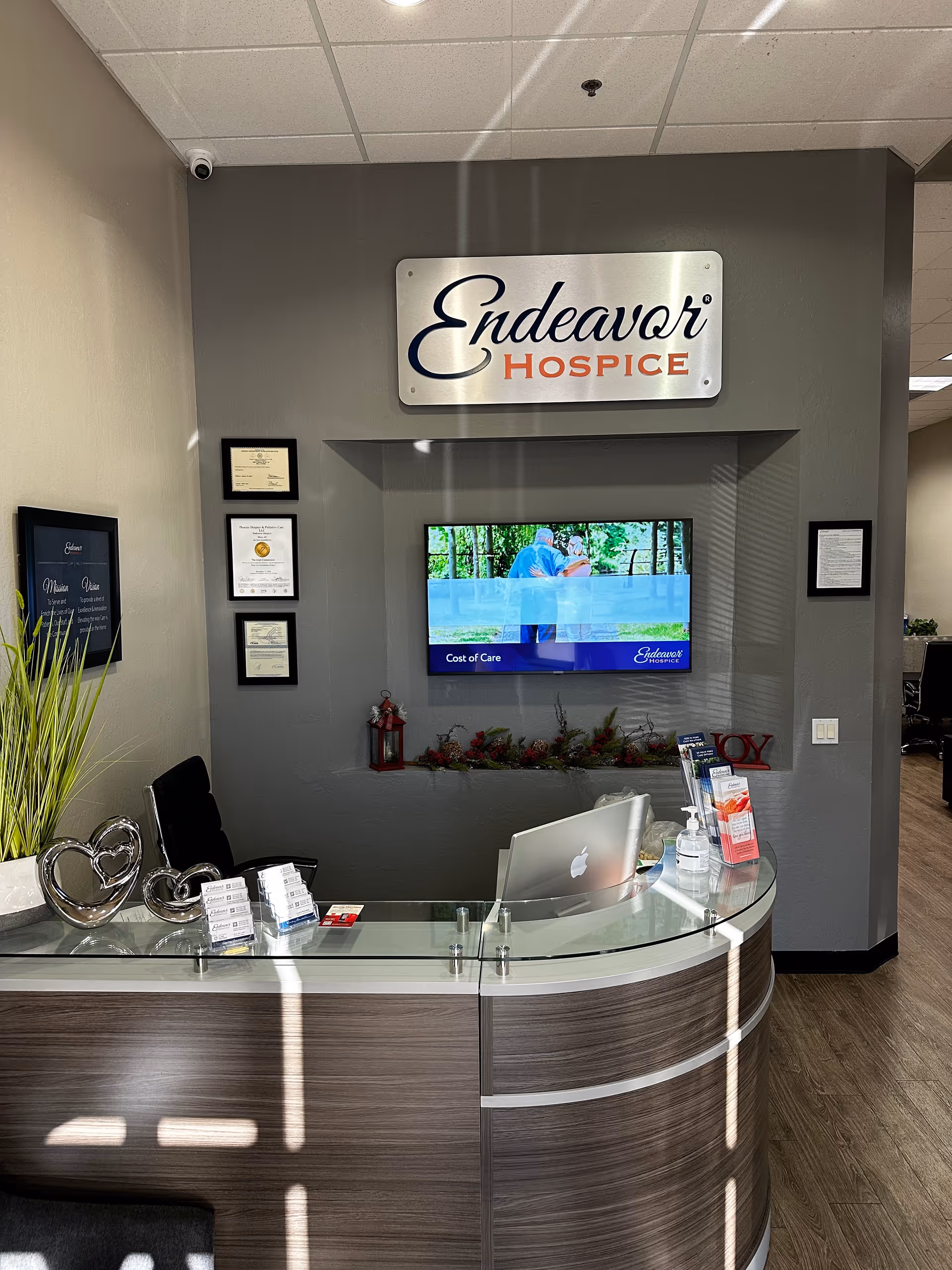 Reception desk in a gray-walled lobby with Endeavor Hospice sign and wall certificates.