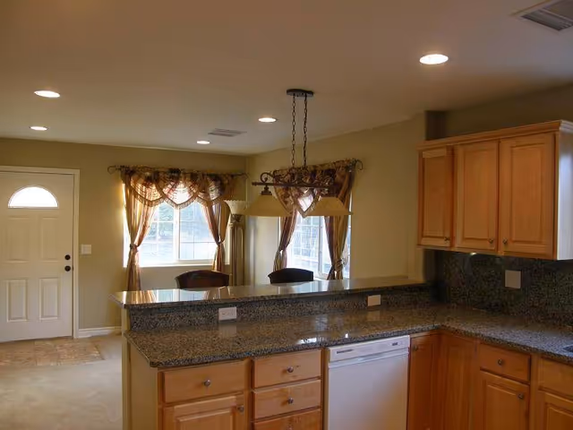 Bright kitchen with granite countertops, wooden cabinets, island, and breakfast bar.