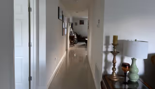 Bright hallway in a senior living facility with wall art and furniture along the corridor.