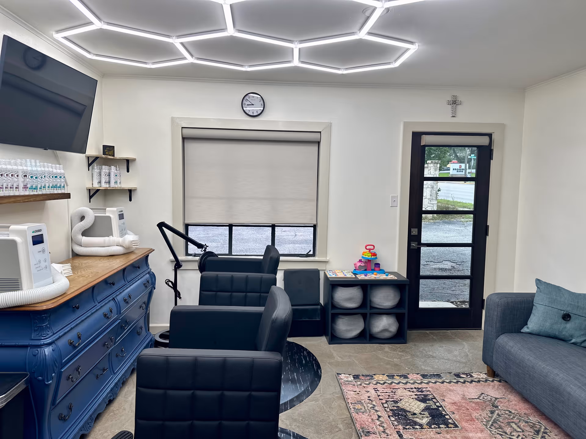 Indoor senior living facility salon/lounge featuring a blue dresser, chairs, shelves, and a couch.