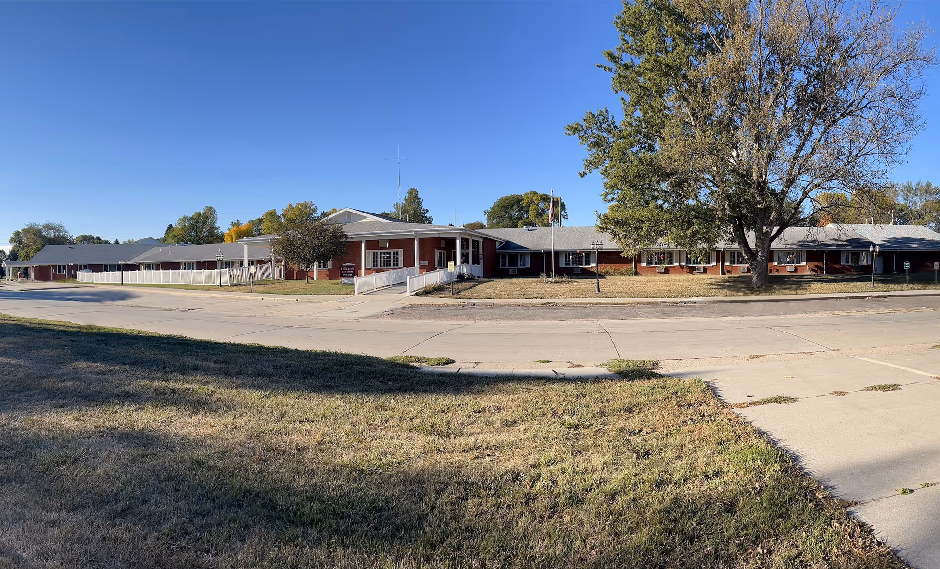 Exterior view of Hillcrest Assisted Living building along a tree-lined street
