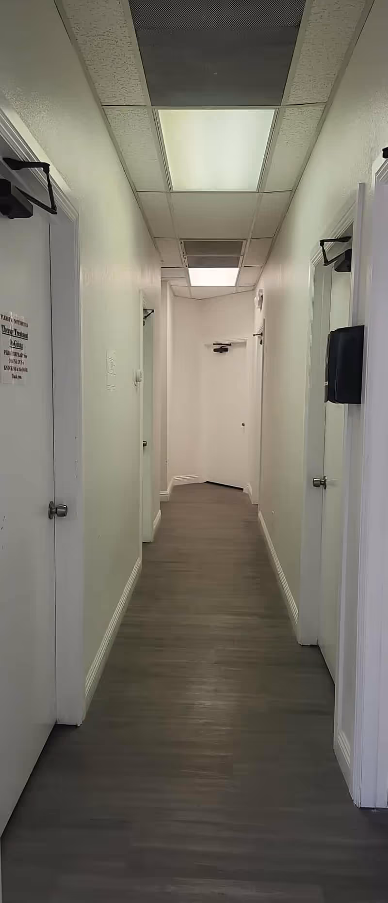 A narrow, well-lit hallway with doors on both sides in a senior care facility.