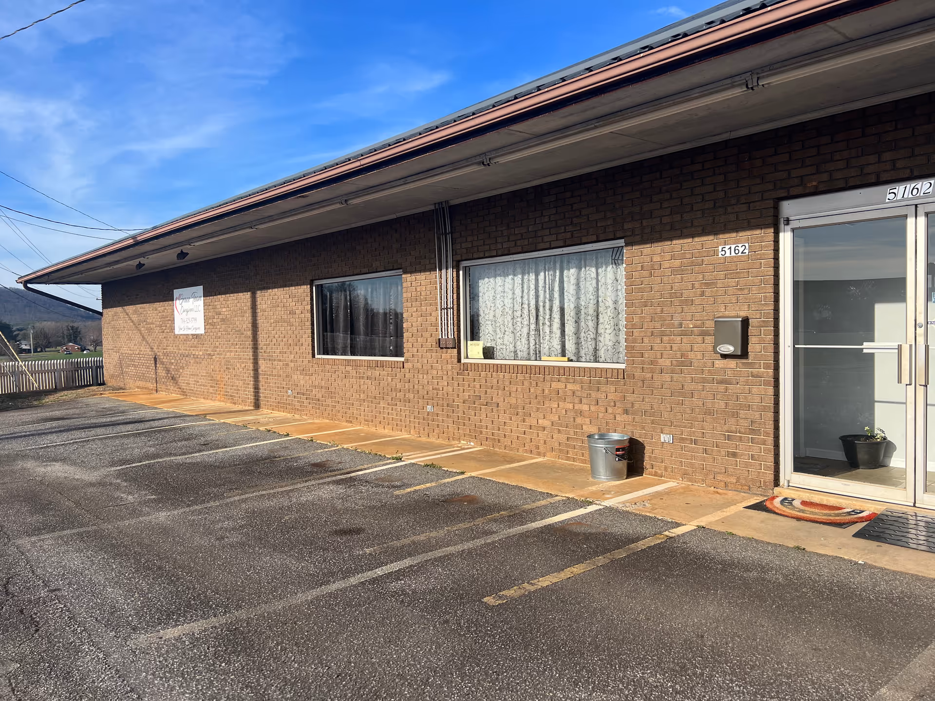 Brick, single-story building with a glass front entrance and a paved parking lot.
