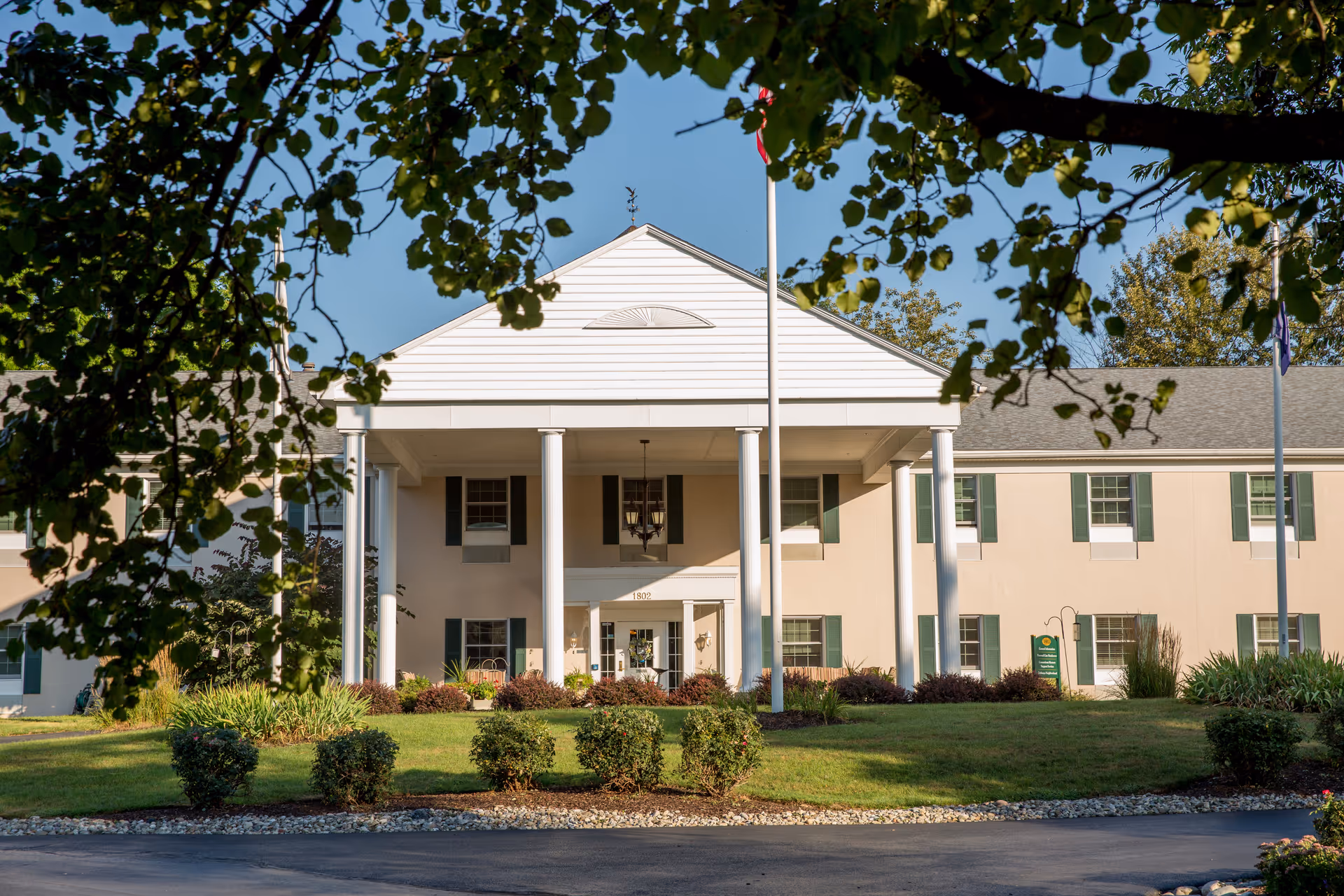 Front view of Country Meadows of Wyomissing with columns, entrance, and manicured landscaping.